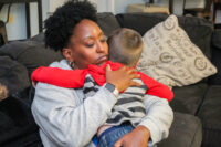 african american woman hugging caucasian little boy