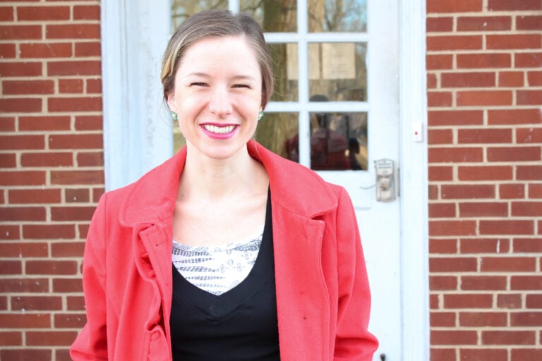 author standing outside in red coat smiling