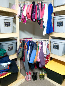 closet with bins and hangers of clothes