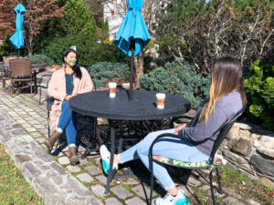 therapist and teen girl sitting at outdoor table chatting with coffee