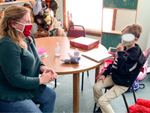 therapist and young boy 7 years of age sitting at table doing therapy