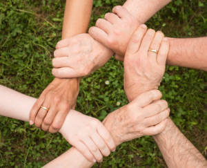 six hands holding wrists linked in a circle