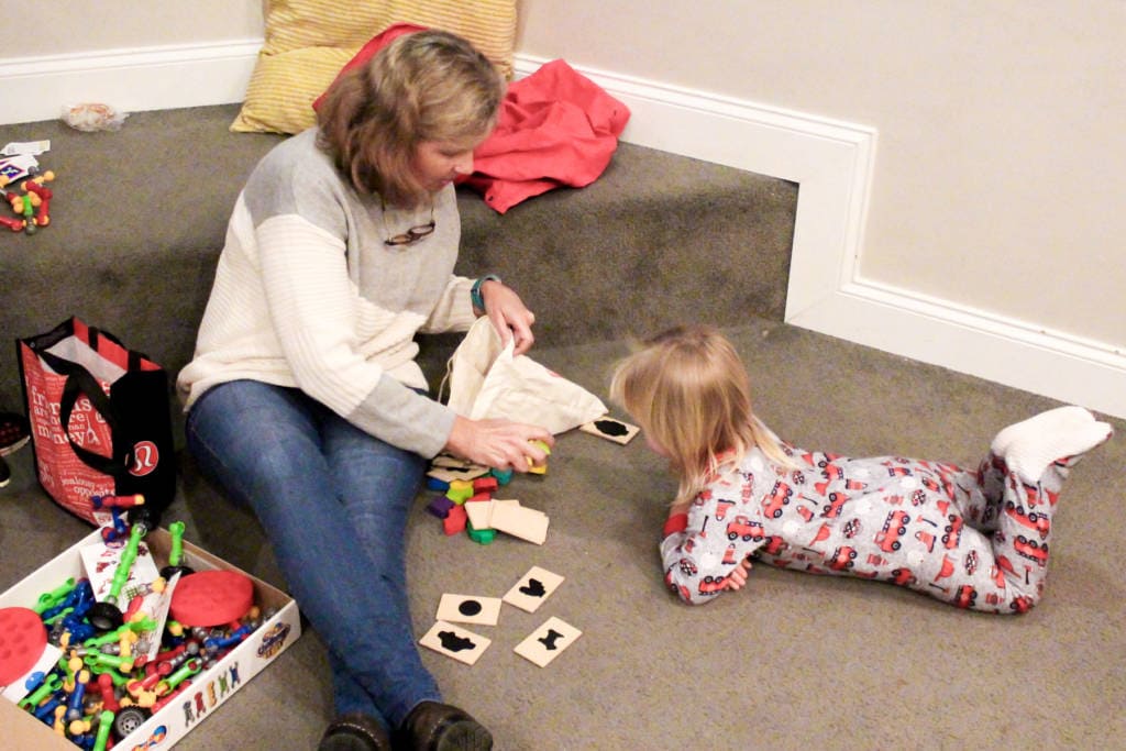 lady sitting on floor helping a child with a puzzle book