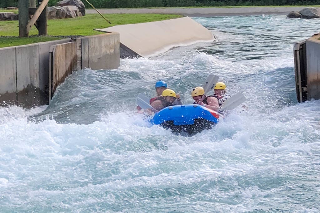 a group of people whitewater rafting in a blue boat