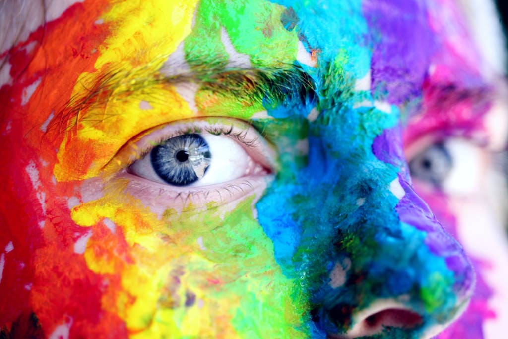 youth with rainbow painted face up close eye shot