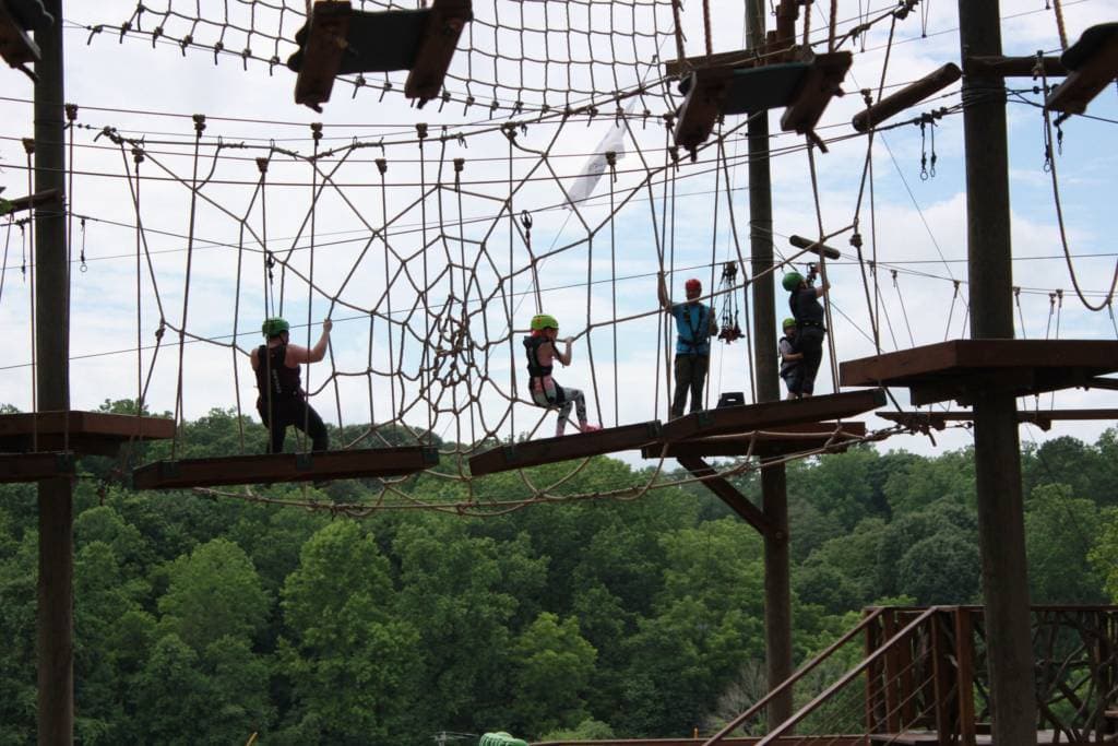 people on a high ropes course spider net