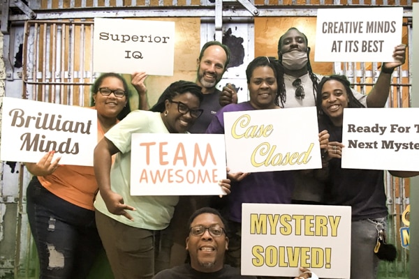 crossnore's day treatment staff holding up signs in a huddle after completing an escape room