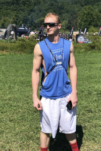 teen boy stands in field looking to his right