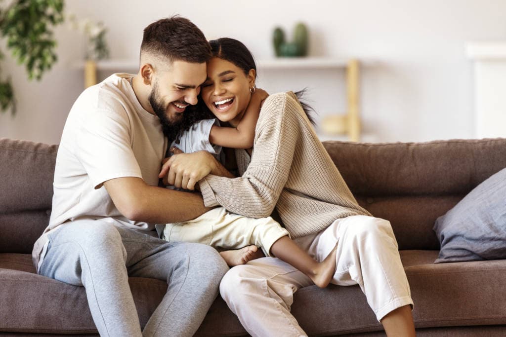 white father, biracial mother hugging child on couch