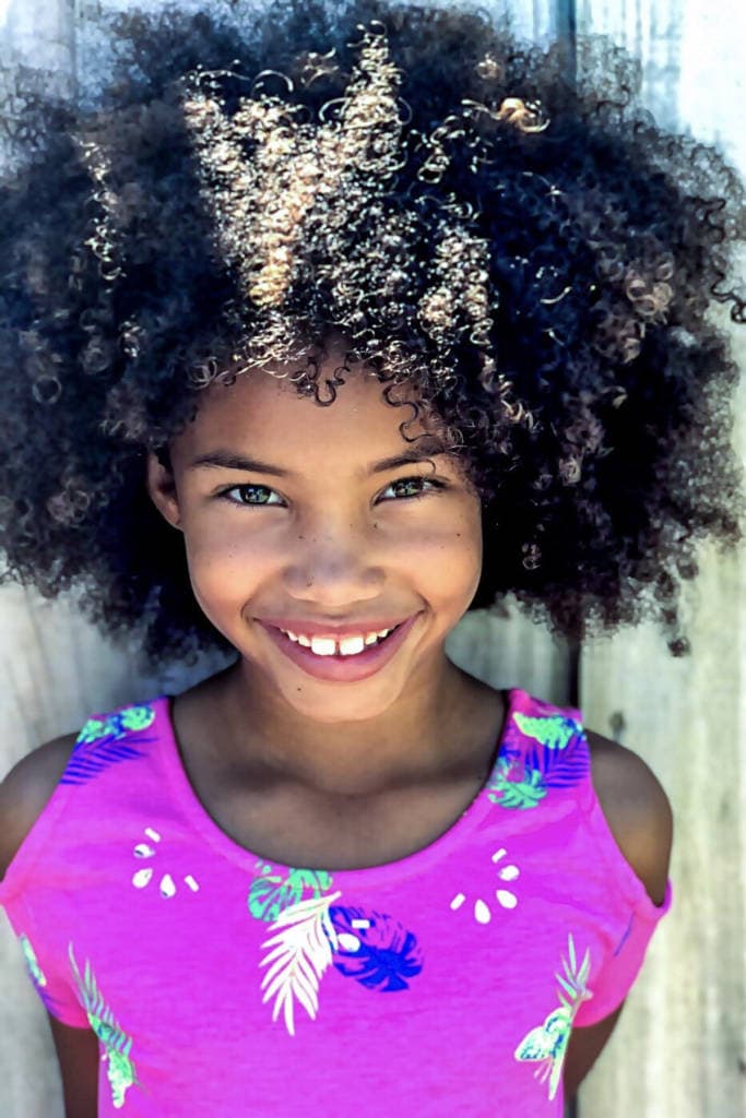 smiling african american girl with afro and pink dress