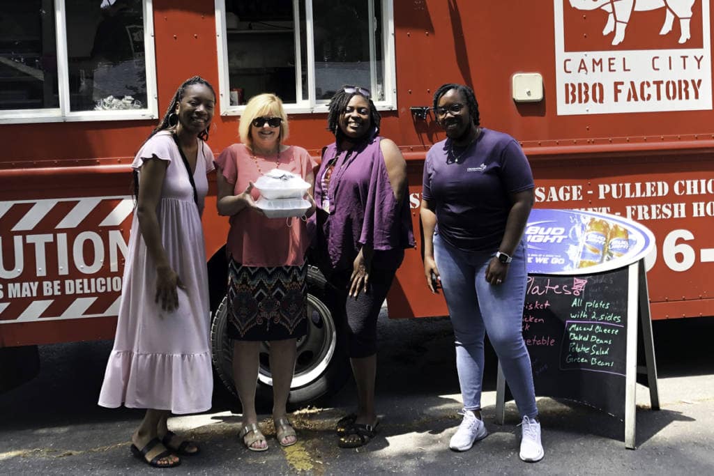 group of diverse crossnore employees standing in front of food truck smiling
