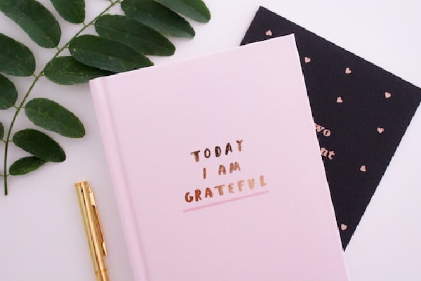 two journals; pink and black with text "Today I am grateful."
