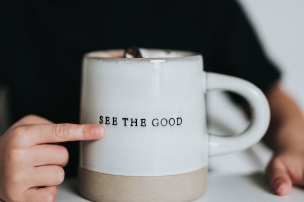 white and beige coffee mug with the words "see the good" 
